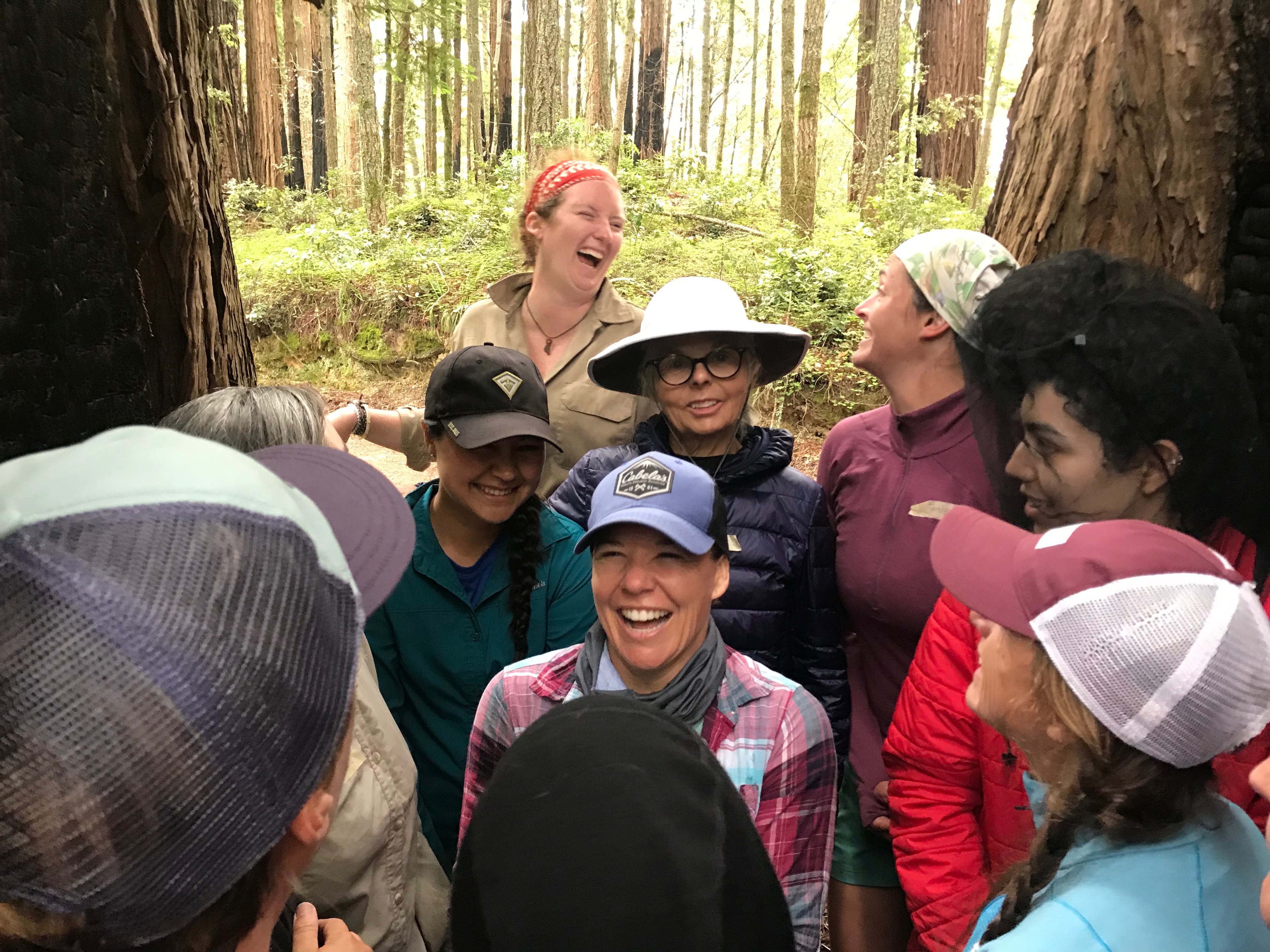 Women's Weekend Participants laughing inside of a chimney tree (redwood) stump